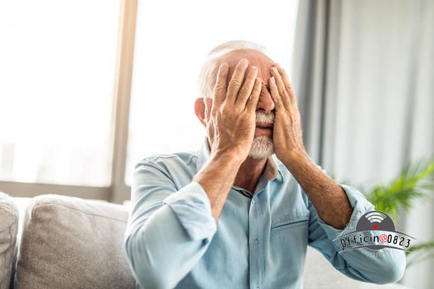 Senior man covering his face in disbelief and grief.